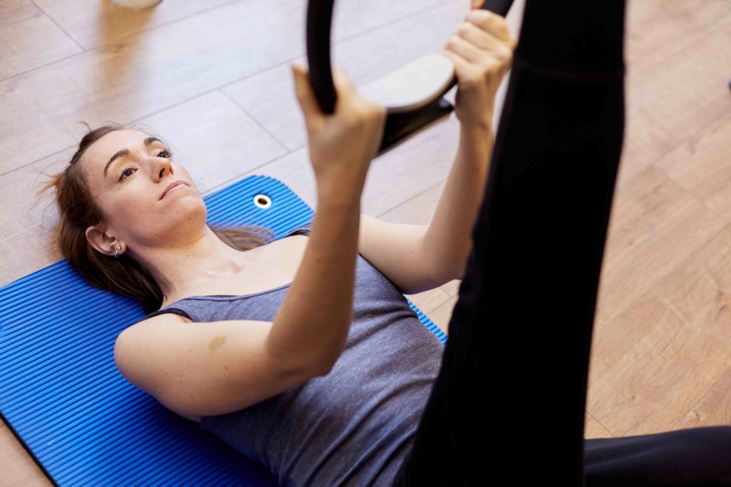 Woman performing a Clinical Pilates exercise with a Pilates ring at Movement Perfected London