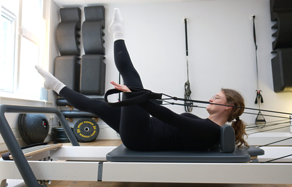 Person using Reformer Pilates machine in Movement Perfected Moorgate Clinic