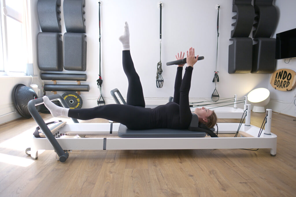 Person using Reformer Pilates in different pose in machine in Movement Perfected Moorgate Clinic